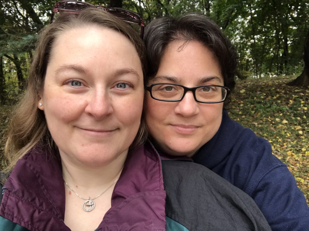 Revs. Diana McLean and Shay MacKay. The photo is of two white women, outdoors, looking at the camera; the one on the right is looking towards us over the shoulder of the other