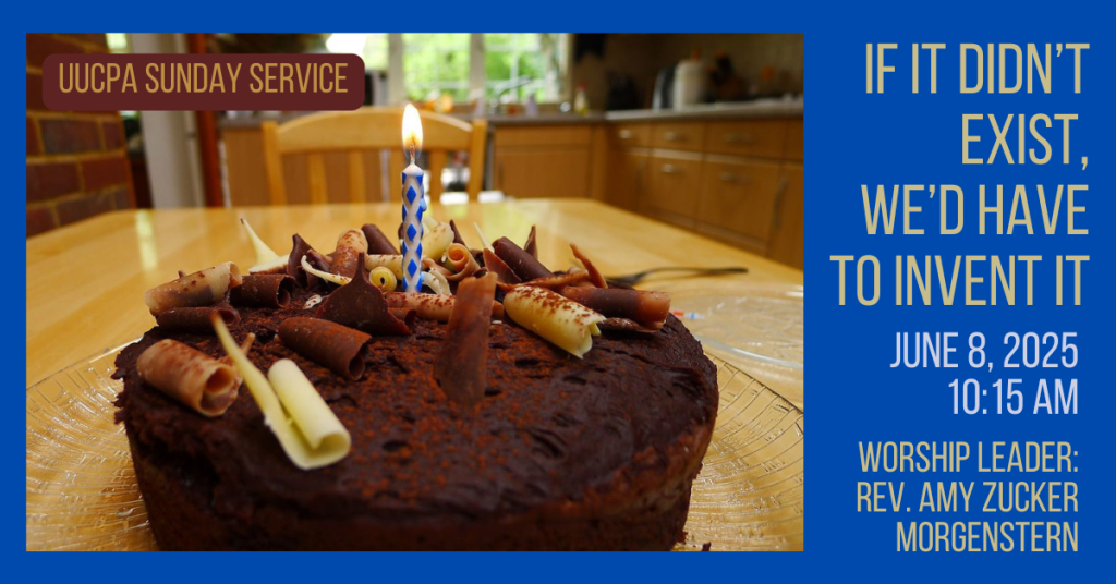 On a wooden kitchen table: a chocolate cake decorated with curls of different kinds of chocolate, and with one blue and white candle burning in its center