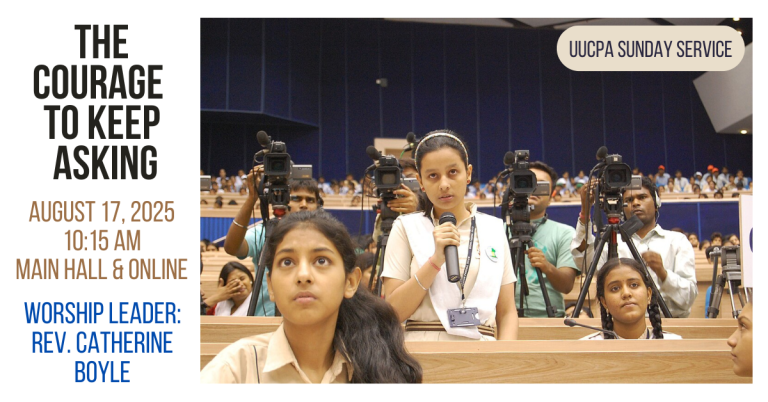 A girl with brown skin and South Asian features standing and speaking into a microphone. Other children are also seated around her, and camera operators are pointing in the direction she is looking.